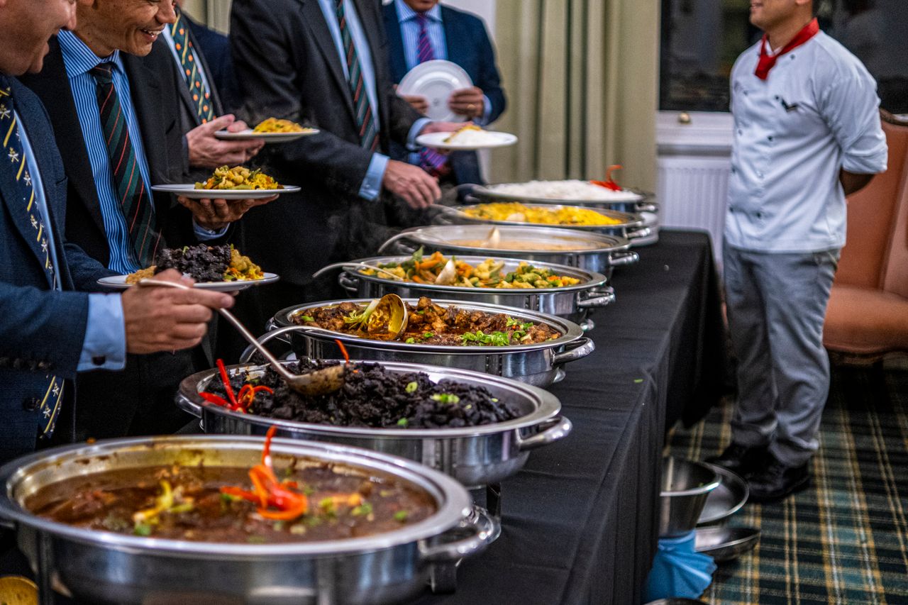 Business professionals in suits enjoy a diverse buffet lunch selection at a formal event.